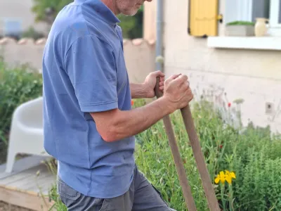 Christophe au travail de profil dans un jardin fleuri devant maison